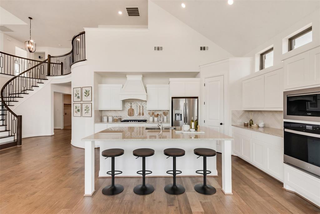 511 San Angelo Drive Forney, TX 75126 - Photo 6 of 34 a kitchen with stainless steel appliances kitchen island granite countertop a table chairs in it and wooden floors