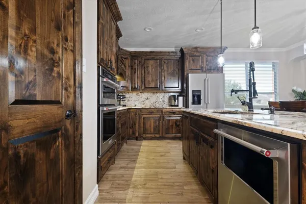 a kitchen with stainless steel appliances granite countertop wooden floors and a view of living room