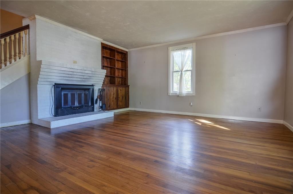 716 Killian Hill Road Southwest Lilburn, GA 30047 - Photo 11 of 56 a view of an empty room with wooden floor fireplace and a window