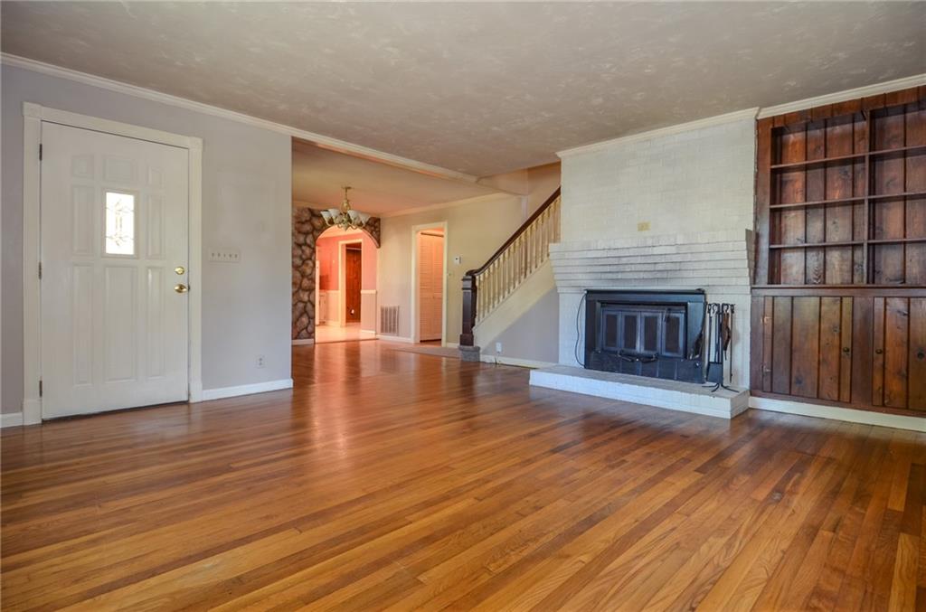 716 Killian Hill Road Southwest Lilburn, GA 30047 - Photo 13 of 56 an empty room with wooden floor fireplace and windows