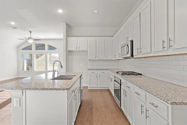a large kitchen with cabinets appliances a sink and a counter top space