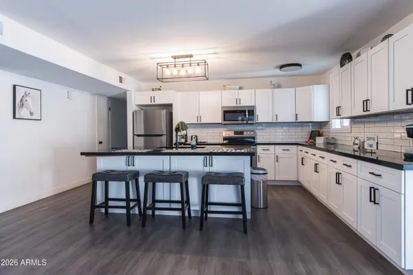 a kitchen with stainless steel appliances a white table chairs and a refrigerator
