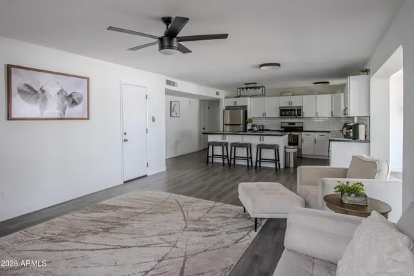 a living room with couches and kitchen view with wooden floor