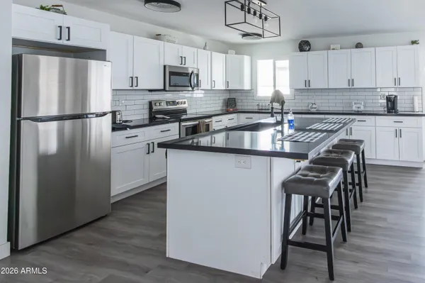 a kitchen with stainless steel appliances granite countertop a refrigerator a stove a sink dishwasher a microwave oven with a dining table and chairs