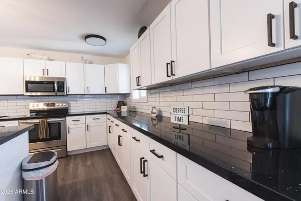 a kitchen with granite countertop white cabinets stainless steel appliances and sink