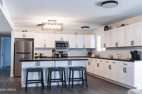 a kitchen with stainless steel appliances granite countertop a table chairs sink and cabinets