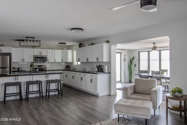 a large white kitchen with granite countertop a stove a sink a dining table and chairs