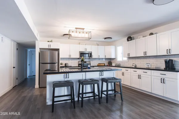 a kitchen with granite countertop a table chairs microwave and cabinets