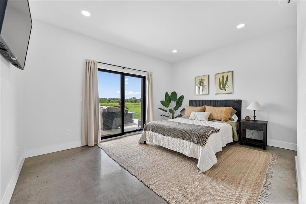 9082 Wolf Run Krum, TX 76249 - Photo 12 of 38 a spacious bedroom with a large bed and a chandelier