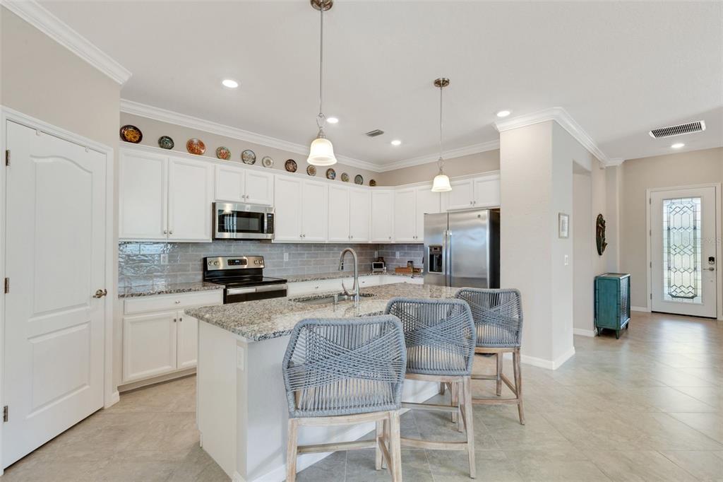 20573 Trattoria Loop Venice, FL 34293 - Photo 11 of 46 a kitchen with stainless steel appliances kitchen island granite countertop a stove a sink a refrigerator and white cabinets with wooden floor