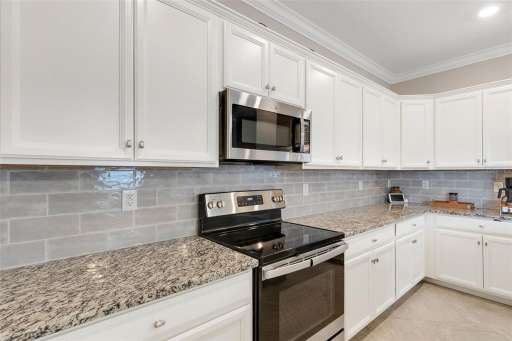 20573 Trattoria Loop Venice, FL 34293 - Photo 12 of 46 a kitchen with granite countertop white cabinets and stainless steel appliances
