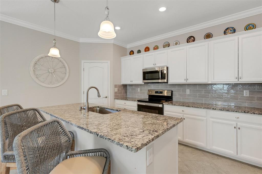 20573 Trattoria Loop Venice, FL 34293 - Photo 10 of 46 a kitchen with granite countertop stainless steel appliances a sink a stove top oven a chimney and a center island