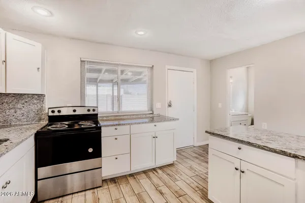a kitchen with granite countertop white cabinets and black appliances