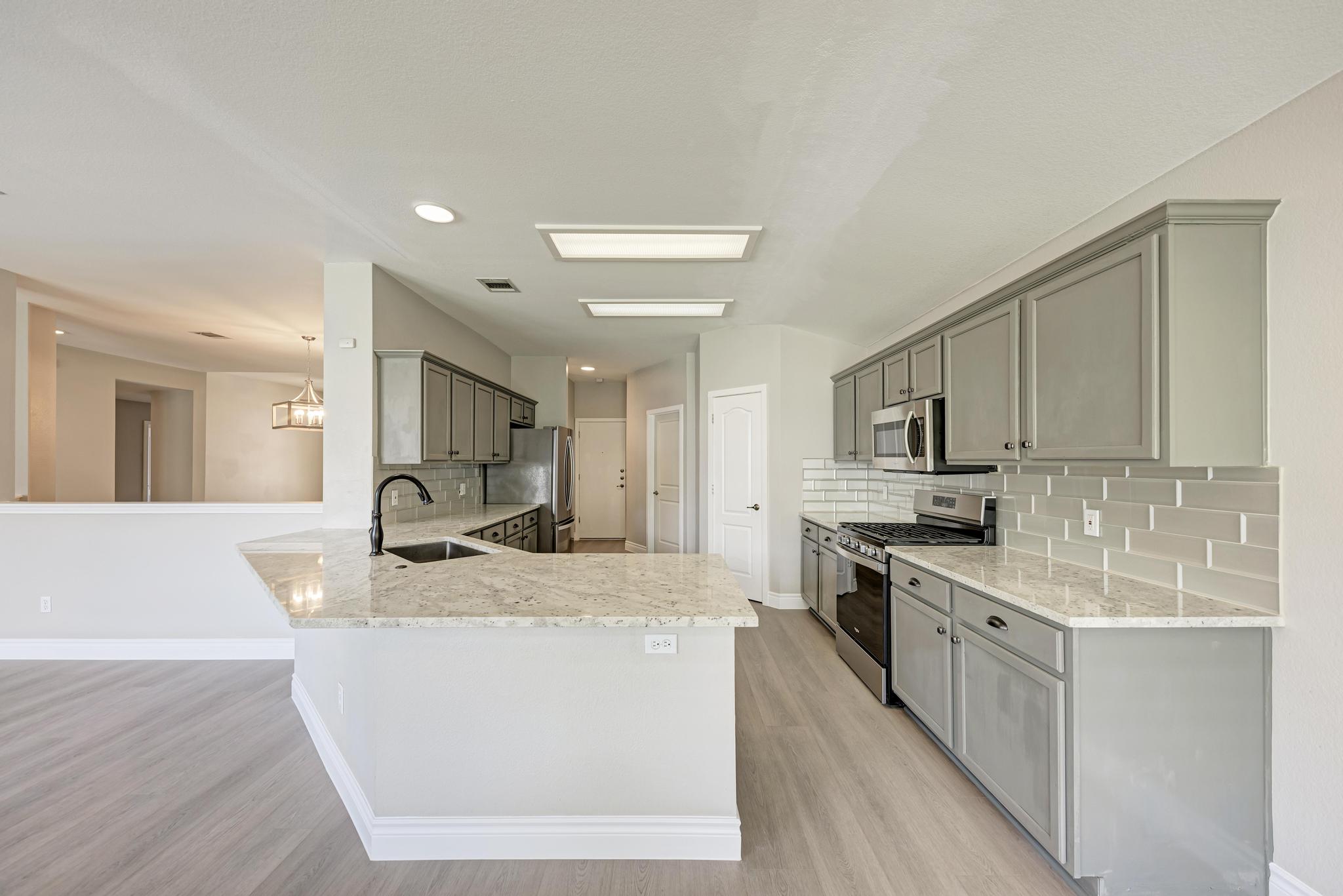 4408 Tello Path Austin, TX 78749 - Photo 15 of 38 Kitchen with stainless steel appliances, tasteful backsplash, a peninsula, light stone countertops, and light wood-type flooring
