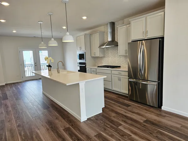 a kitchen with stainless steel appliances a refrigerator a sink a center island and wooden floor