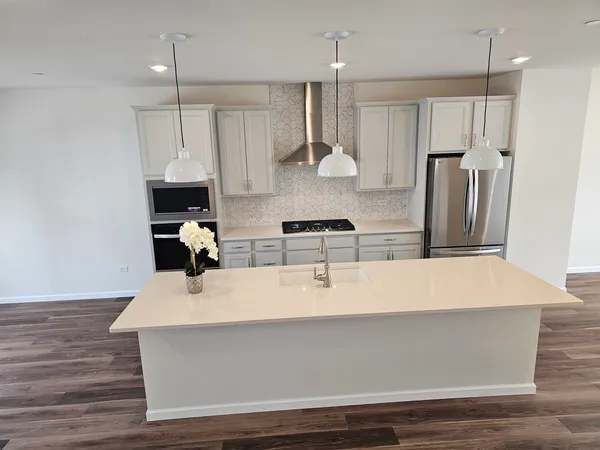 a large kitchen with stainless steel appliances a large counter top and wooden floors