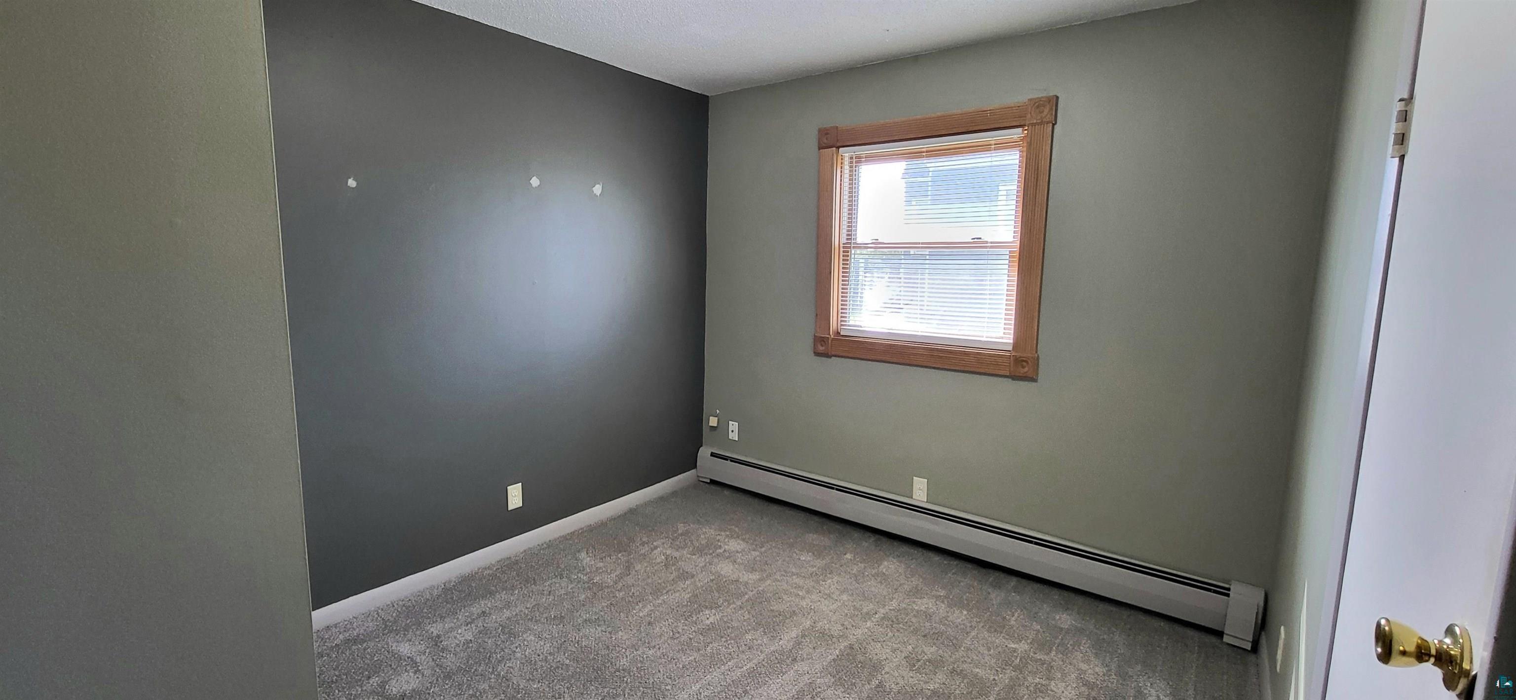 56 East 2nd Street Superior, WI 54880 - Photo 13 of 18 Carpeted room featuring a single window with wood trim, baseboard heating, and two-tone wall finishes