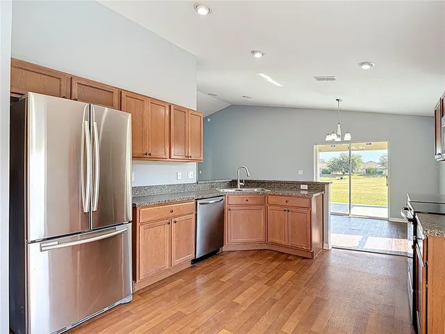 a kitchen with stainless steel appliances granite countertop a stove top oven a sink a counter space and cabinets
