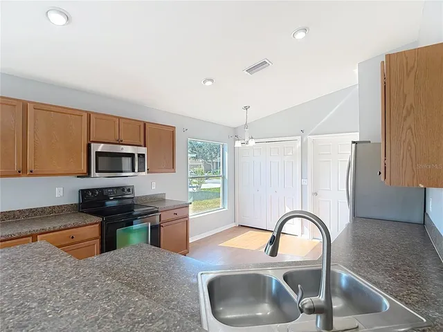 a kitchen with granite countertop a refrigerator a sink and dishwasher