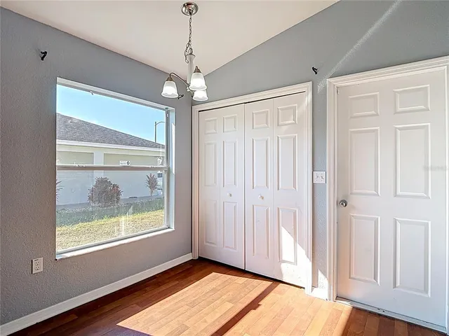 an empty room with chandelier fan and windows
