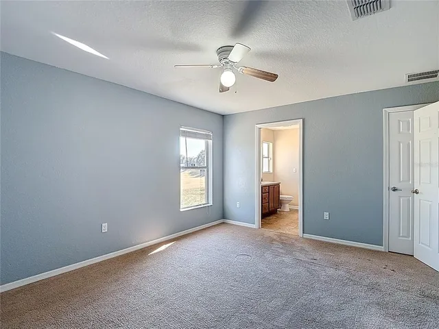 an empty room with a fan & a ceiling fan