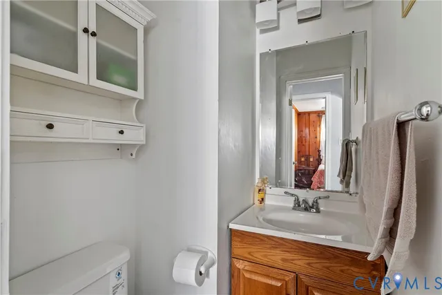 a bathroom with a granite countertop sink vanity mirror and toilet
