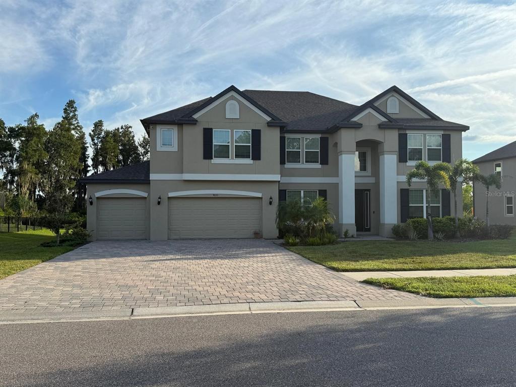 a view of a white house next to a yard and large trees