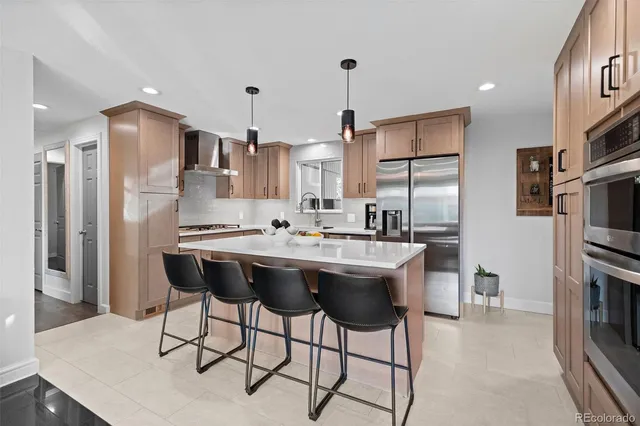 a kitchen with stainless steel appliances kitchen island granite countertop a sink a refrigerator and chairs