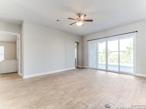 a view of an empty room with chandelier fan and fire place