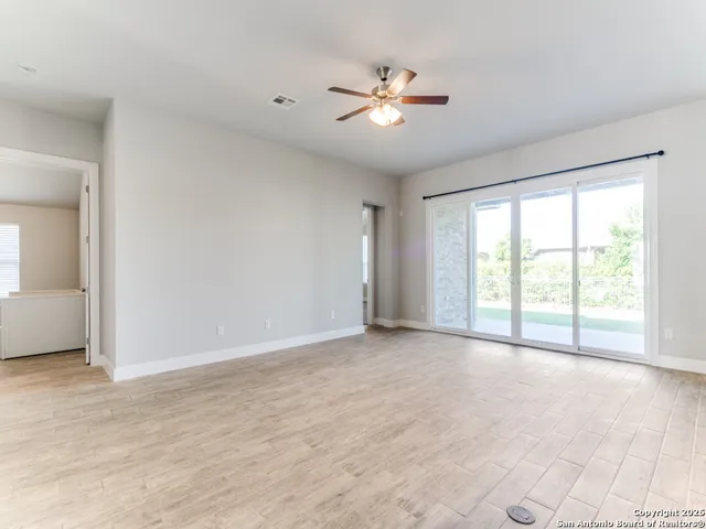 a view of an empty room with chandelier fan and fire place