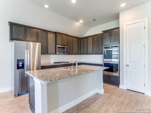 a kitchen with stainless steel appliances granite countertop a refrigerator and a sink