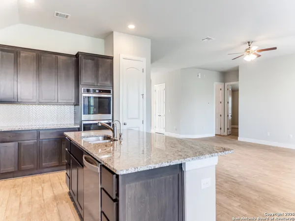 a kitchen with stainless steel appliances granite countertop a sink refrigerator and cabinets