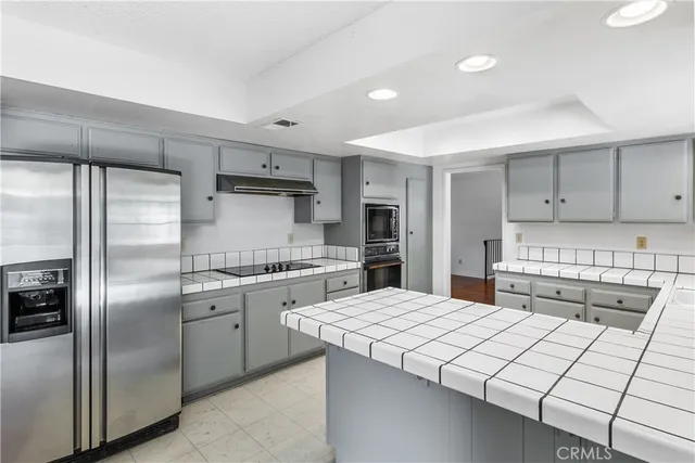 a kitchen with stainless steel appliances kitchen island granite countertop a refrigerator a stove and a sink