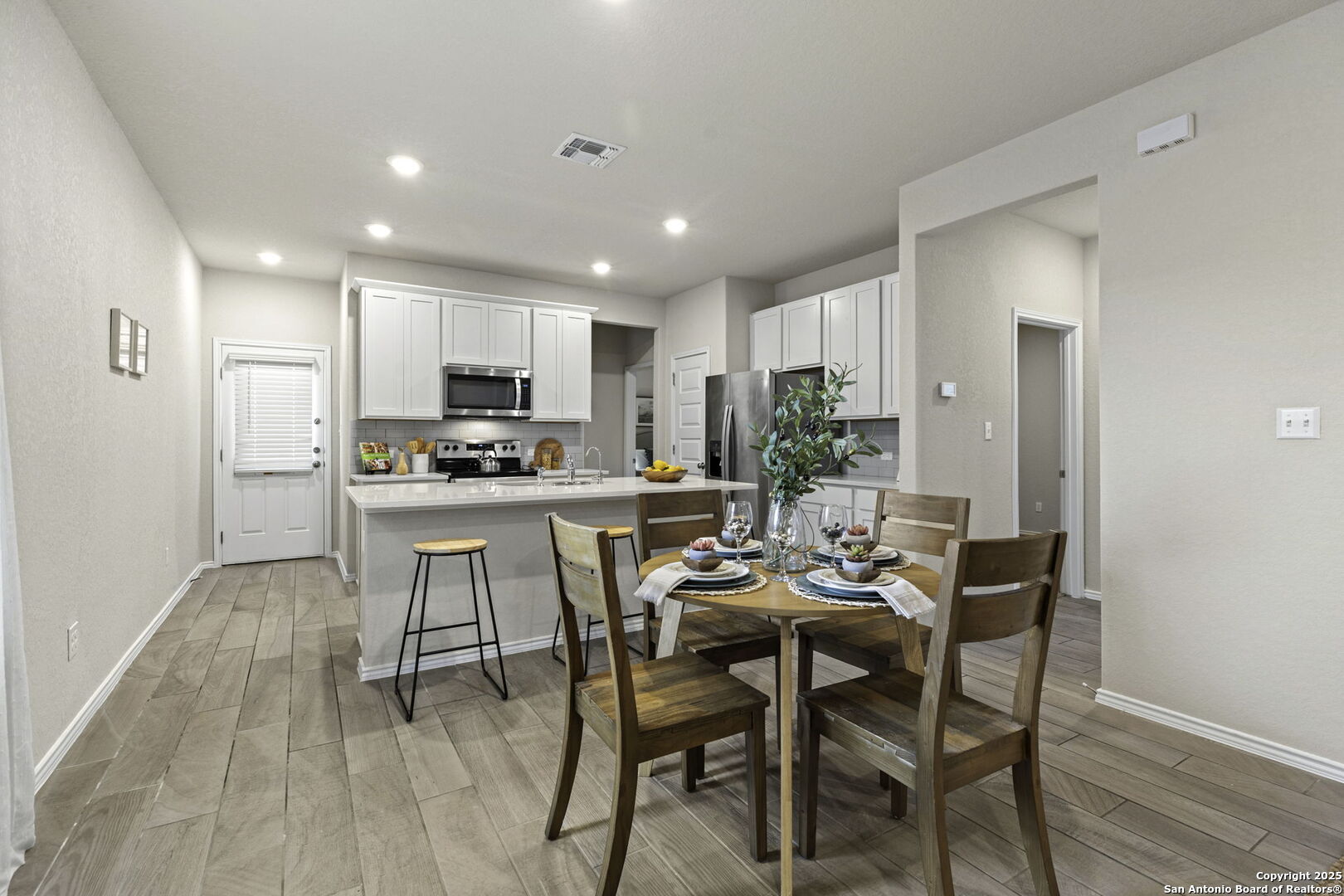 a kitchen with a dining table chairs and refrigerator