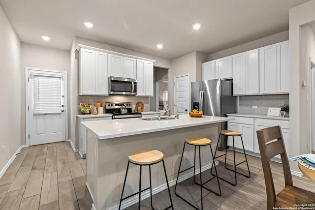 a kitchen with a sink a microwave a refrigerator and white cabinets