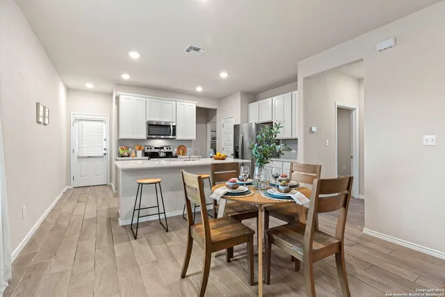 a kitchen with a dining table chairs and refrigerator