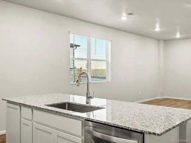a kitchen with granite countertop a sink and a white wooden cabinets