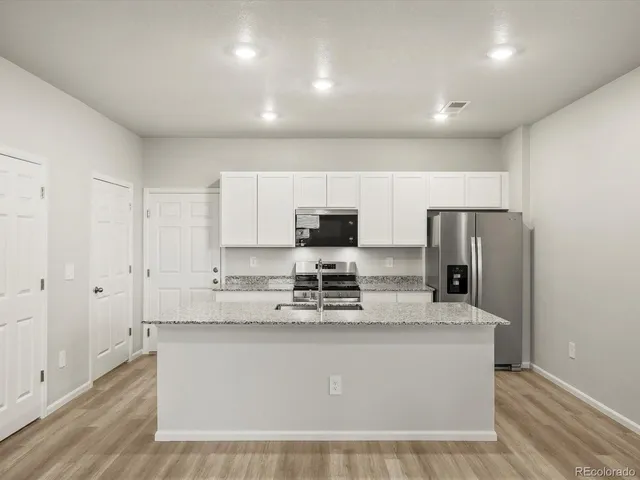 a view of kitchen with stainless steel appliances granite countertop white cabinets and refrigerator