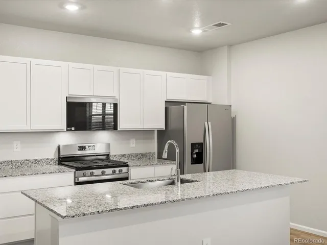 a kitchen with stainless steel appliances granite countertop a sink refrigerator and microwave