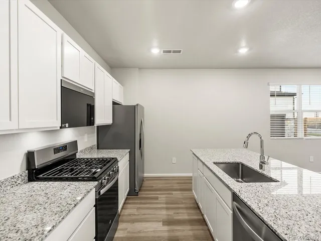 a kitchen with stainless steel appliances granite countertop a sink stove and refrigerator