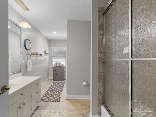 a bathroom with a glass shower door a sink and a bathtub