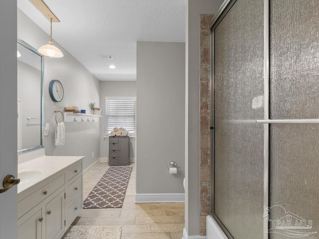 10152 Bittern Drive Pensacola, FL 32507 - Photo 21 of 45 a bathroom with a glass shower door a sink and a bathtub