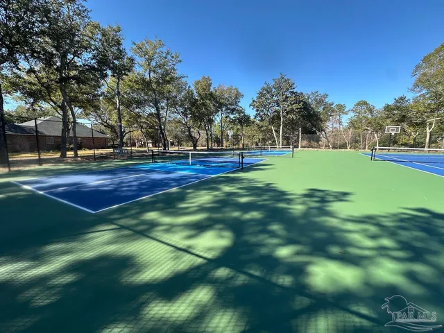 a view of a tennis ground with large trees