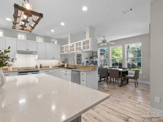 a kitchen with counter space wooden floor dining table and stainless steel appliances