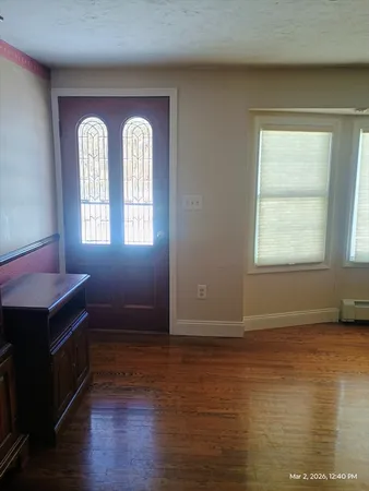 a view of an empty room with wooden floor fireplace and a window