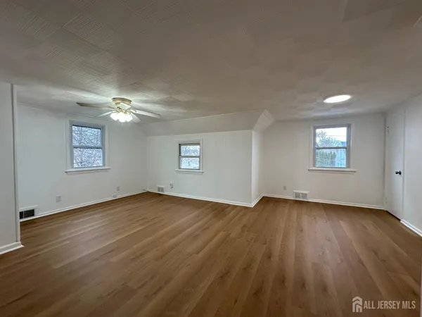 an empty room with wooden floor chandelier and windows
