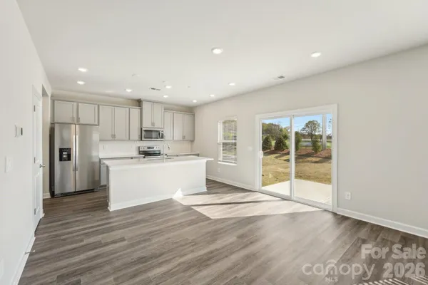 a view of kitchen with granite countertop refrigerator oven sink and white cabinets with wooden floor
