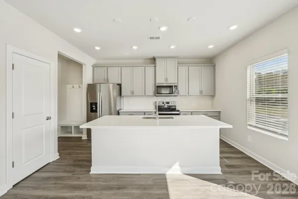 a view of a kitchen with kitchen island a sink wooden floor and a refrigerator