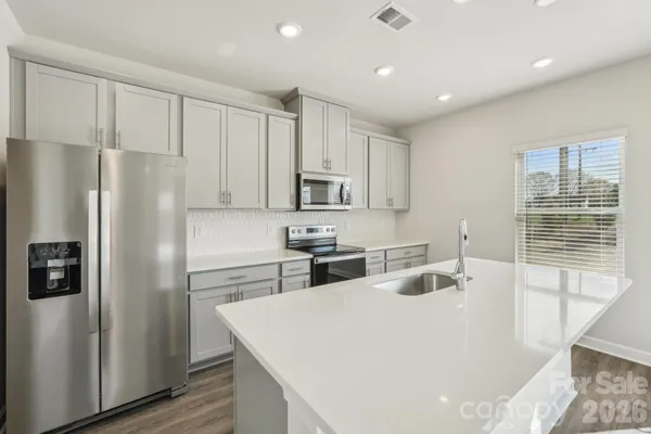 a kitchen with kitchen island a refrigerator sink and cabinets