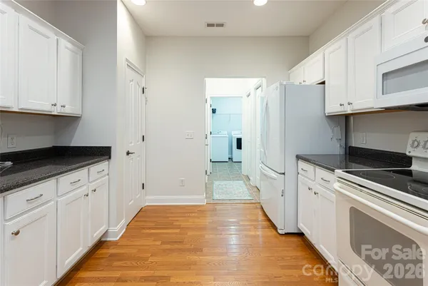 a kitchen with granite countertop white cabinets and white appliances